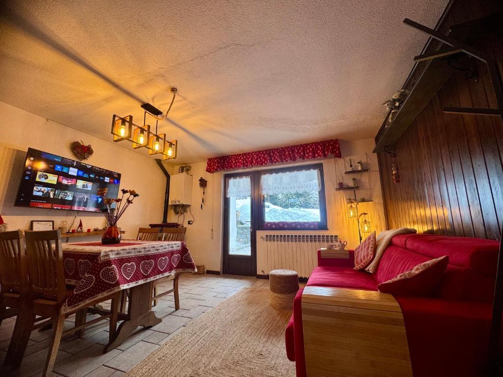 a living room with a red couch and a table at Maison au Soleil in Valtournenche