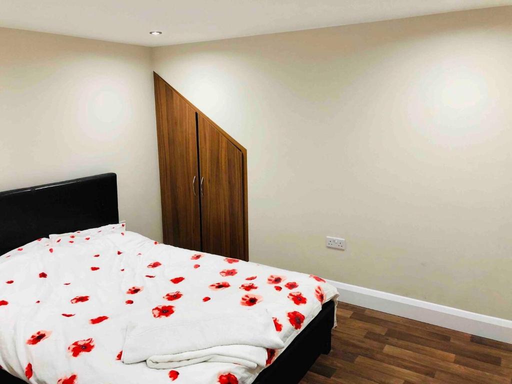 a bedroom with a bed with red roses on it at Small 3 Bed Flat near Heathrow in Staines