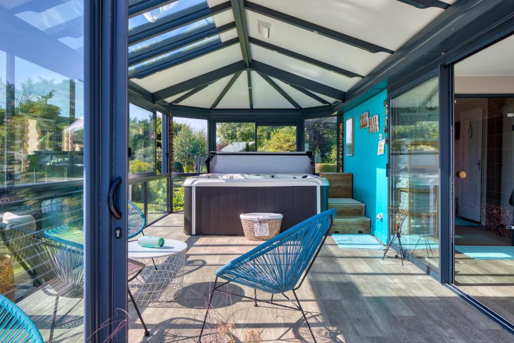 a screened in porch with chairs and a hot tub at Villa Argonne - Cottages & Spa Privatif in Ouville-la-Rivière