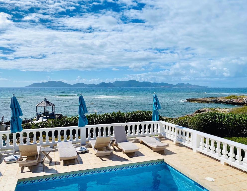 a swimming pool with chairs and a view of the ocean at Lockrum Point Villa - Upscale Ocean Front, Pool with Gazebo in South Hill Village