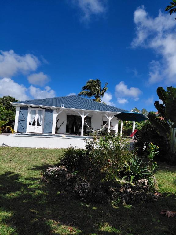 a white house with a palm tree on top of it at Villa de charmes in Capesterre