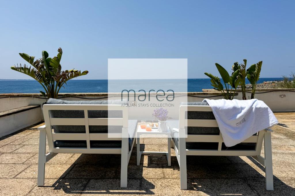 a table and two chairs sitting next to the ocean at Villa Nauna - Beachfront Villa with Garden & Sea-View Terrace Santa Caterina - Marea Stays Collection in Nardò