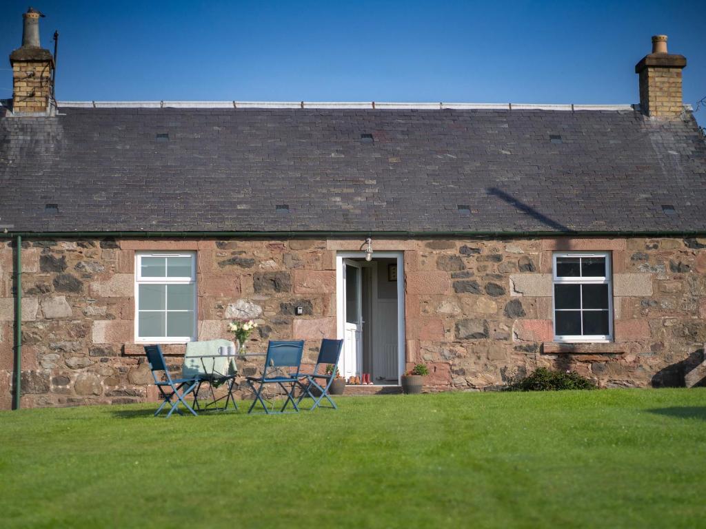 a brick house with two chairs and a table in the yard at The Bothy in Blairgowrie