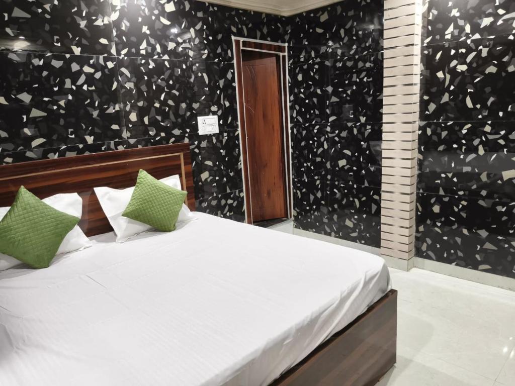 a bedroom with a white bed with green pillows at Braj Darshan Bhawan in Jāmb