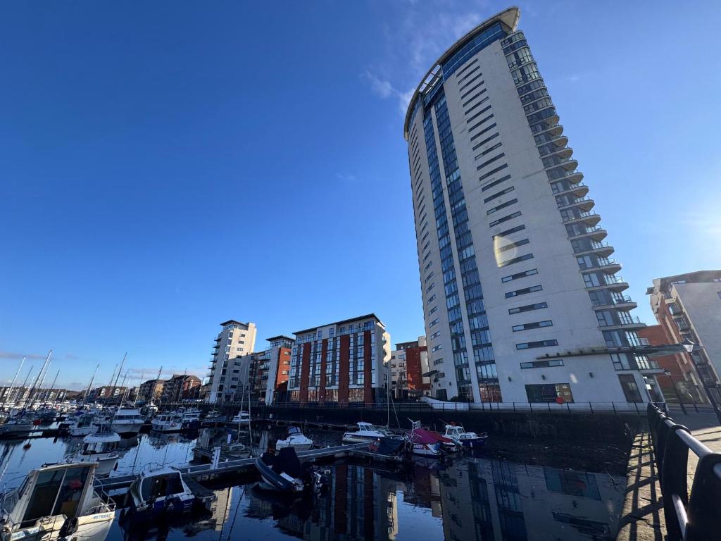 a tall building next to a marina with boats at Three bed apartment in the Tower in Swansea