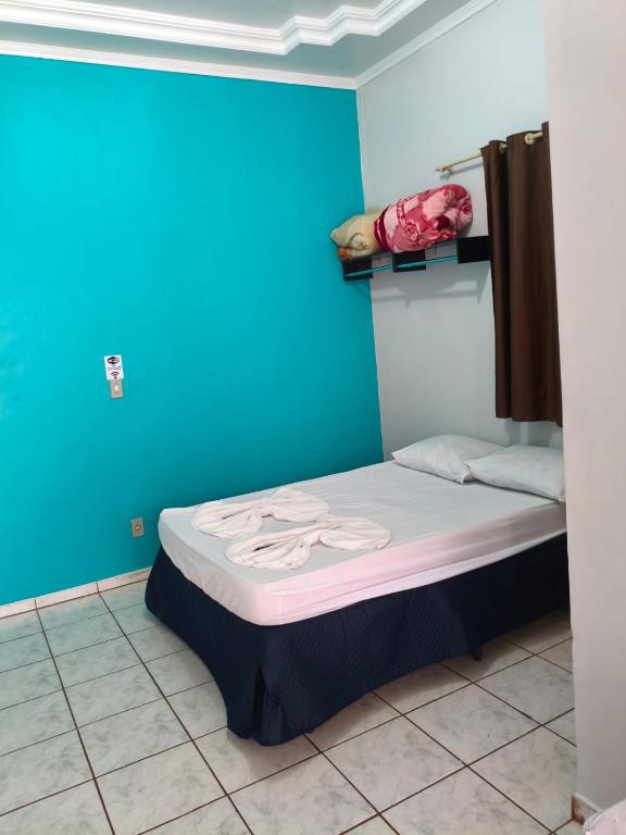 a small bed in a room with a blue wall at Pousada Costa Brasil Engenheiro Beltrao in Engenheiro Beltrão