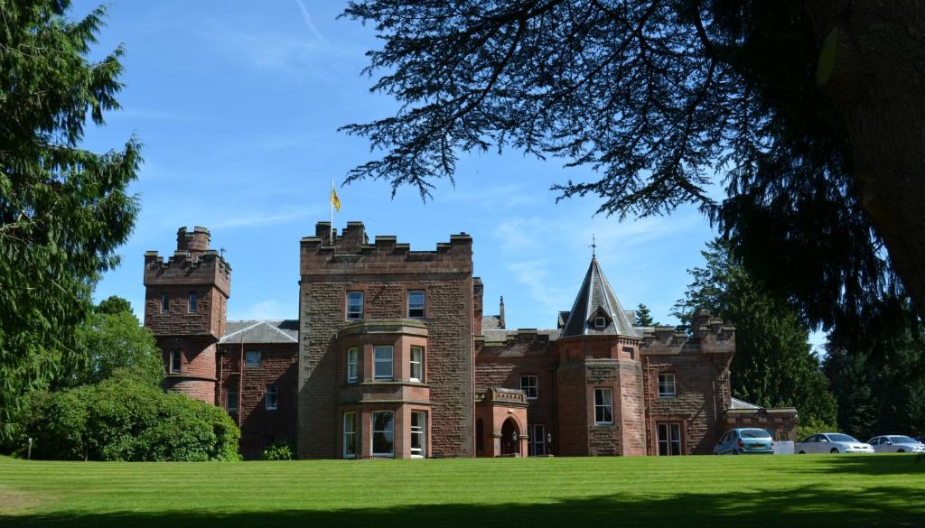 an old castle with a grassy field in front of it at Friars Carse Country House Hotel in Dumfries