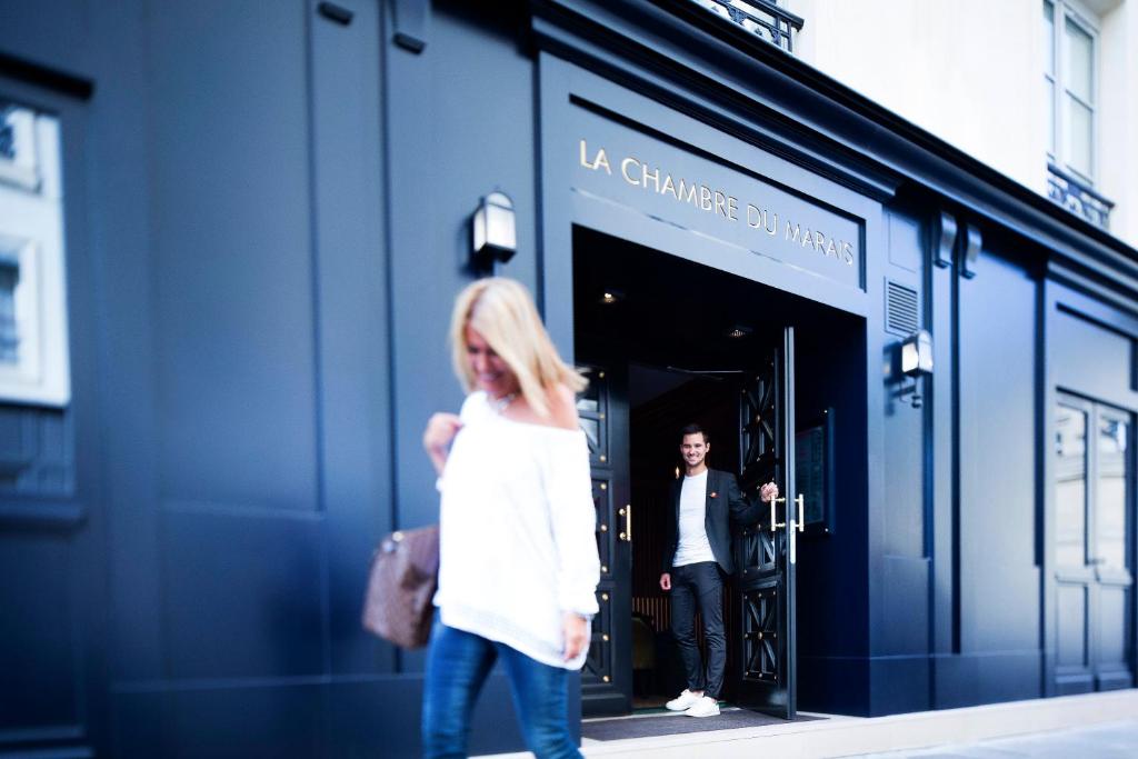 uma mulher andando em frente a uma loja em La Chambre du Marais em Paris