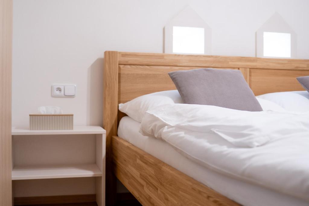 a wooden bed with white sheets and pillows at Ubytování U Mecha in Bečice