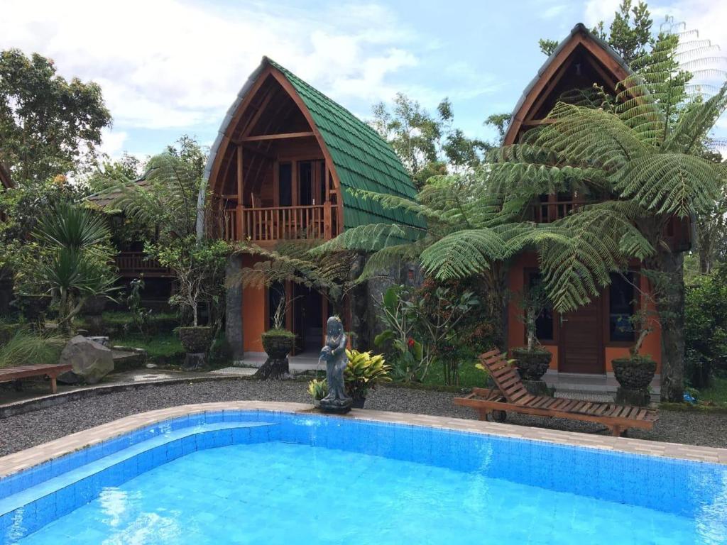a villa with a swimming pool in front of a house at Sandan Agro Resort Kintamni in Kintamani