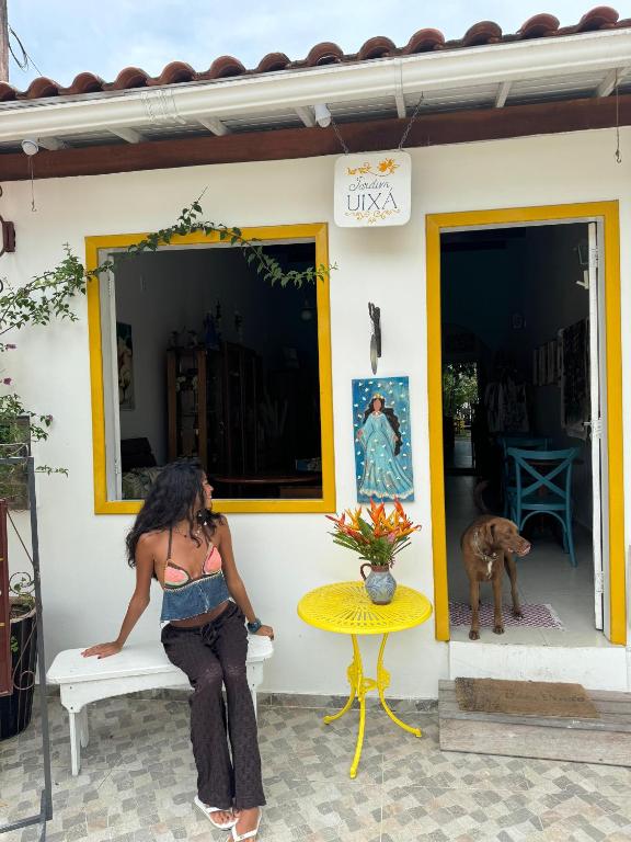 a woman sitting on a bench talking on a cell phone at Jardim UIXA in Ilha de Boipeba