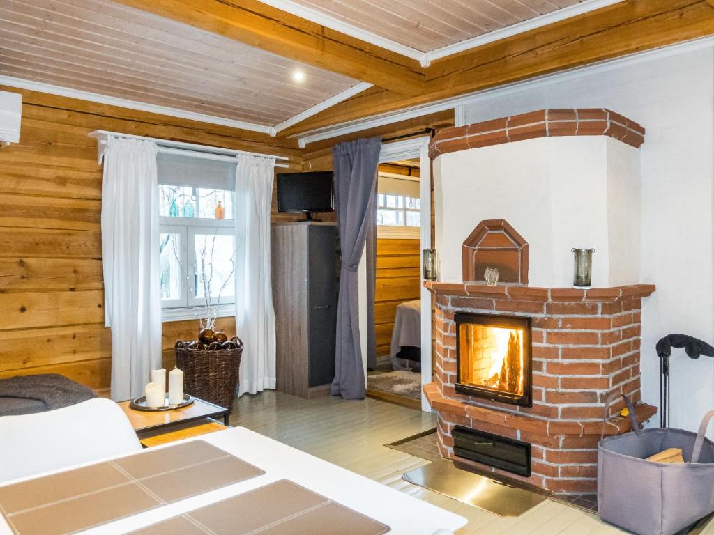 a living room with a brick fireplace and wooden walls at Holiday Home Renkitupa by Interhome in Saarenkylä