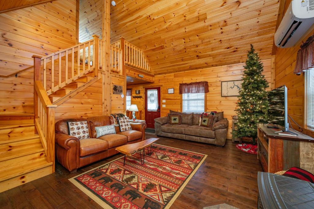 a living room with a staircase in a log cabin at Cozy Cub Cabin by Railey Vacations in McHenry