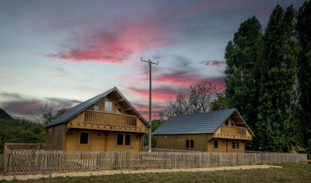 two wooden houses with a fence and a cloudy sky at Owls Nest in Larling