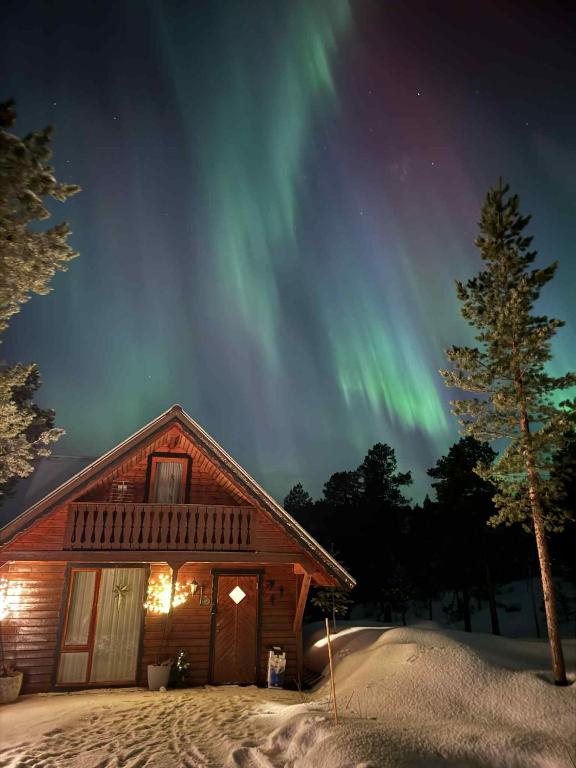 a cabin with the northern lights in the sky at Cozy Mountain Cabin in Senja in Senja