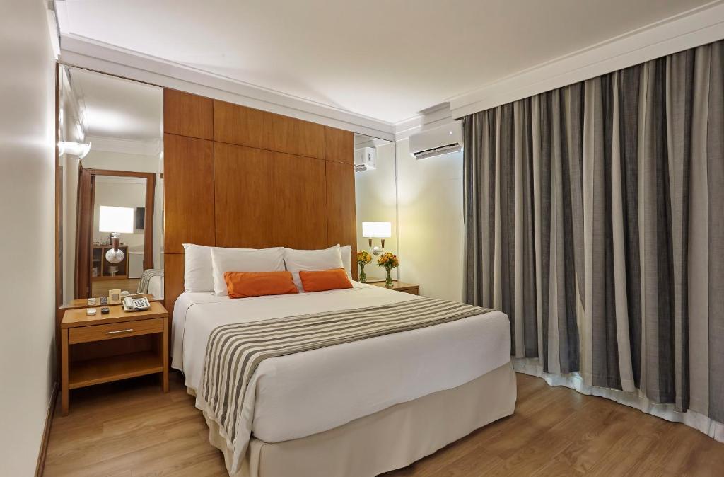 a bedroom with a large white bed with orange pillows at Hotel Cassino Tower Campinas Cambuí By Nacional Inn in Campinas