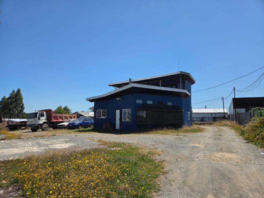 a blue building on the side of a dirt road at Cabañas de Turismo Berolav7 in Puerto Montt