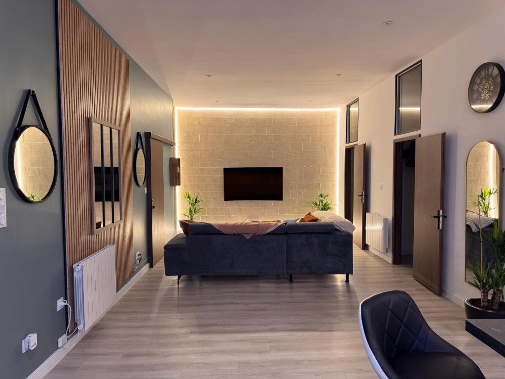 a living room with a bed and a tv on a wall at HOME 102 Cosy in Lons-le-Saunier