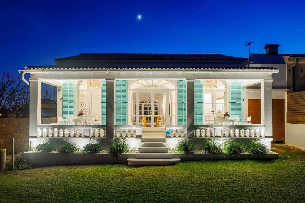 a white house with a porch at night at Veles Dos, villa con piscina frente al mar in Alcudia