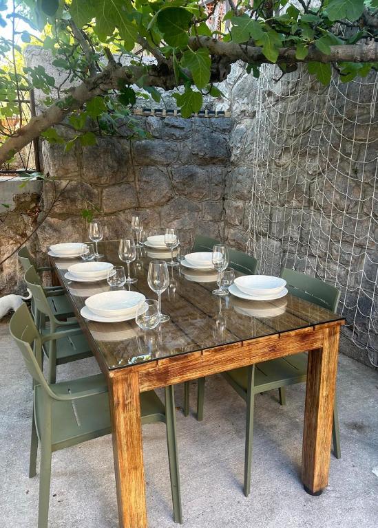 a wooden table with chairs and plates and wine glasses at Casa Bella in Karlobag