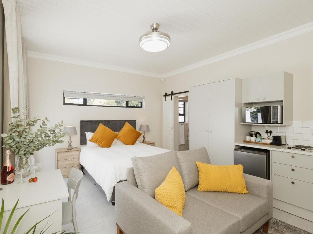 a bedroom with a bed and a couch with yellow pillows at Catalyst Guest House in Cape Town