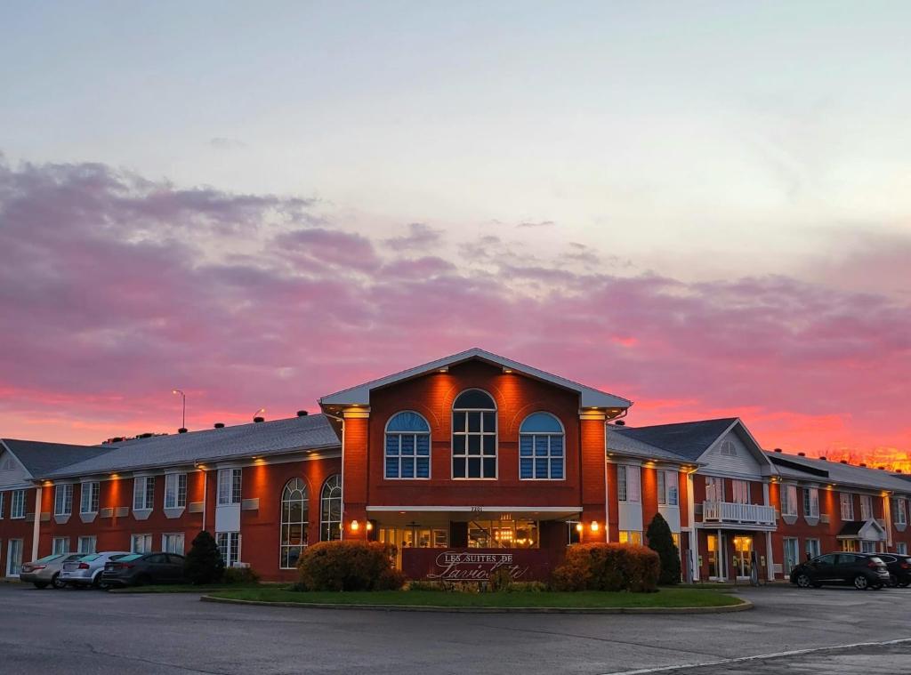 a hotel with cars parked in a parking lot at Les Suites de Laviolette, an Ascend Collection Hotel in Trois-Rivières