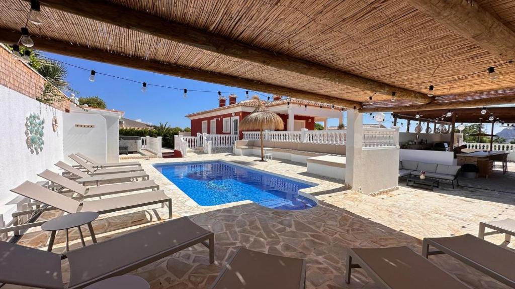a patio with a pool and chairs and a house at Casa Amis Calpe in Calpe
