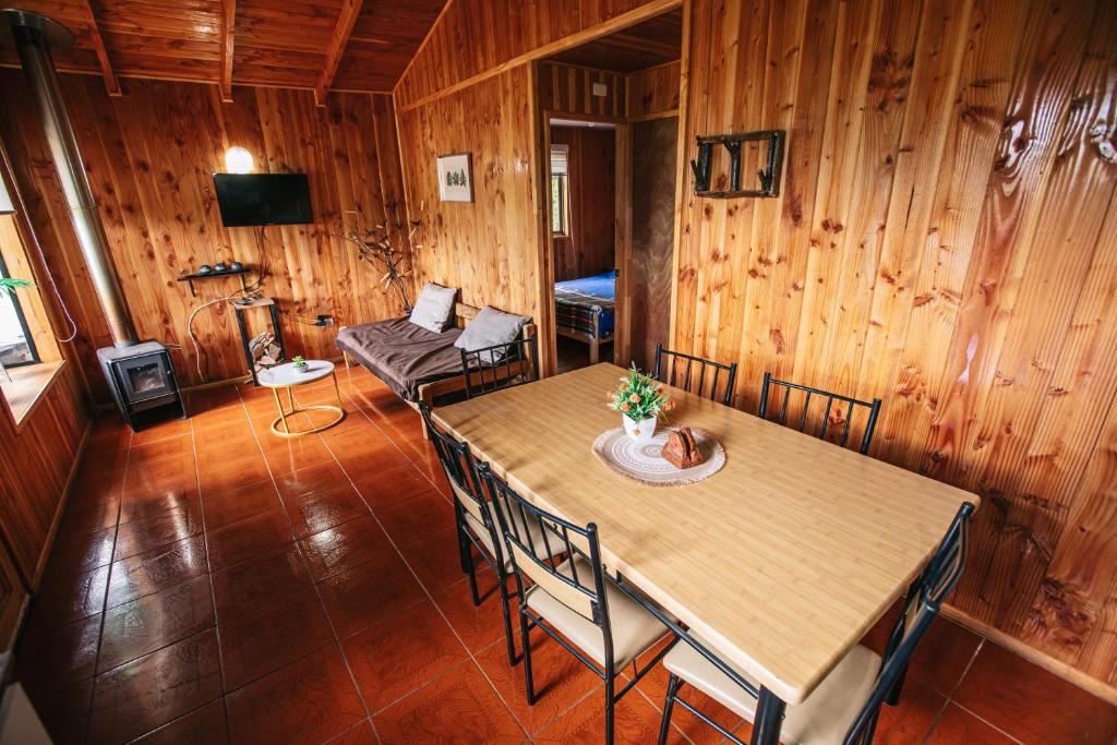 a wooden room with a table and chairs and a couch at Cabañas Ruta Volcán Pucon in Pucón