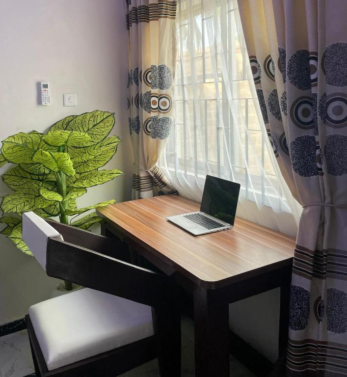 a laptop computer sitting on a desk next to a window at The Grace Villa in Abeokuta