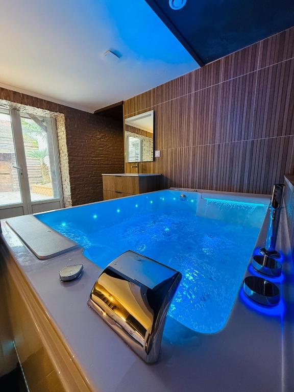 a large blue tub in a bathroom with a sink at Le Cupidon & Spa in Pont-Sainte-Maxence