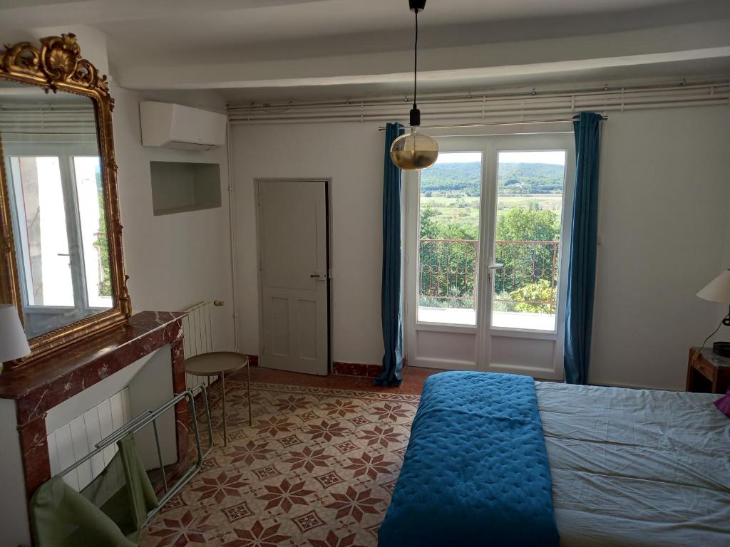 a bedroom with a bed and a mirror and windows at La maison in Cruviers-Lascours