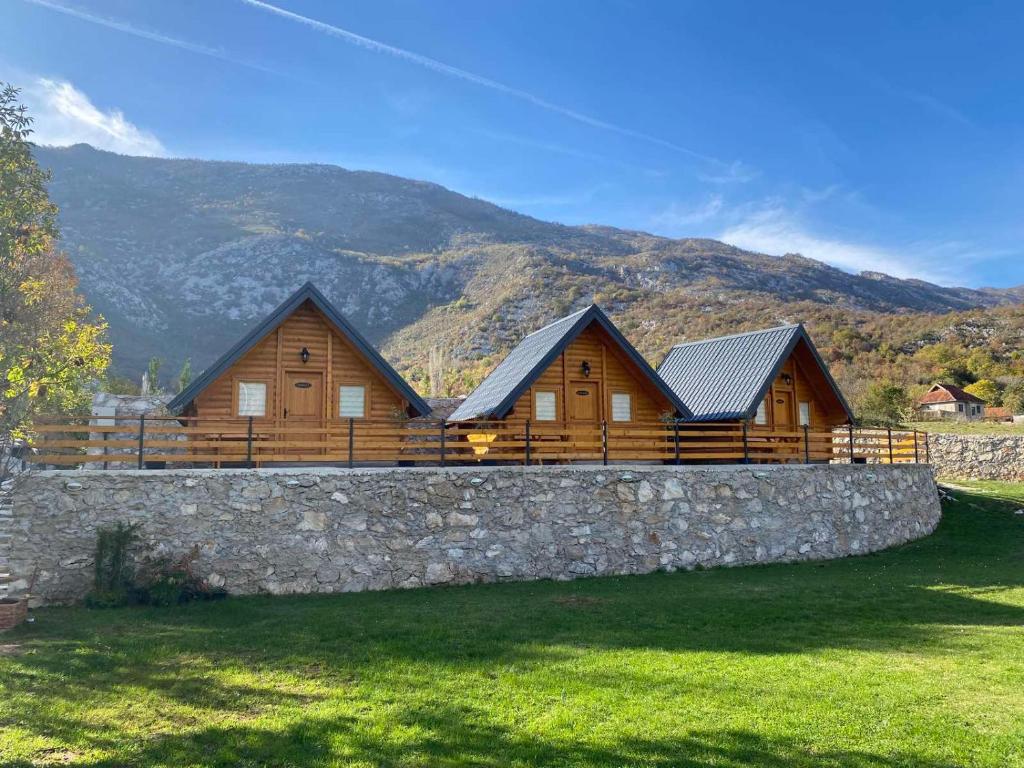 a row of wooden houses behind a stone wall at Etno Lug - Village in Bogetići