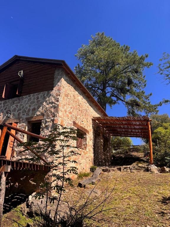 an old stone building with a tree in the background at Stone Cabin, PETRA HAUS in Cuesta Blanca