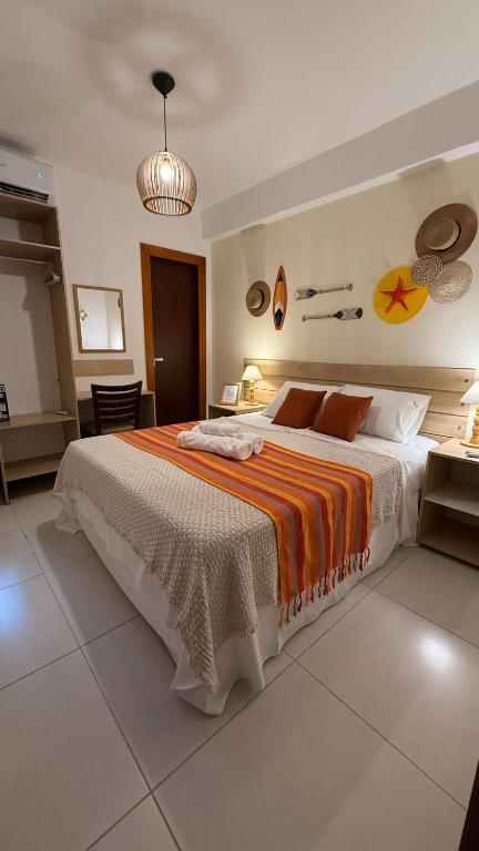 a bedroom with a large bed with an orange and white blanket at Pousada Mar da Vila in Cabo Frio