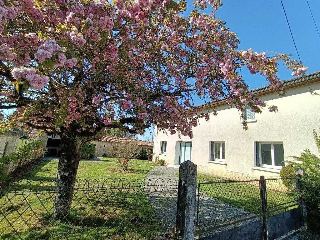 a tree with pink flowers in front of a fence at Location des longères in Brux