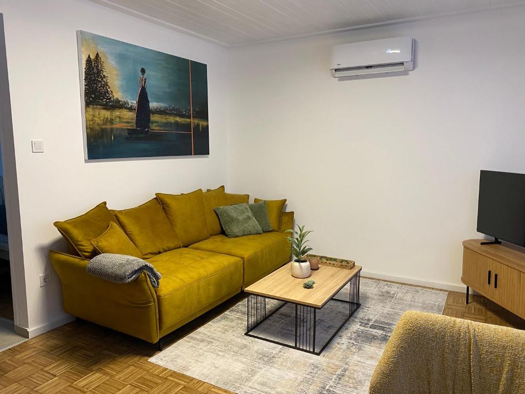 a living room with a yellow couch and a table at Mesebeli ház in Kismaros