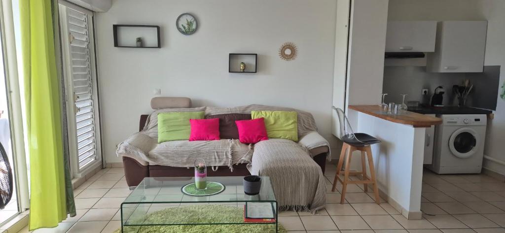 a living room with a couch with pink and green pillows at Au zamana in Le Robert