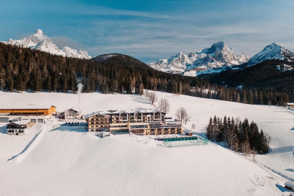 a large building in the snow with snow covered mountains at Hotel Neubergerhof in Filzmoos