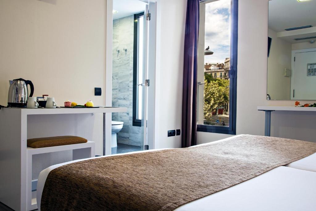 a hotel room with a bed and a window at BCN Urbaness Hotels Del Comte in Barcelona