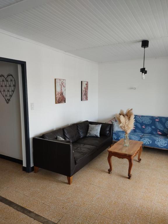 ein schwarzes Sofa in einem Wohnzimmer mit einem Tisch in der Unterkunft Chez Célia in Port-Saint-Louis-du-Rhône