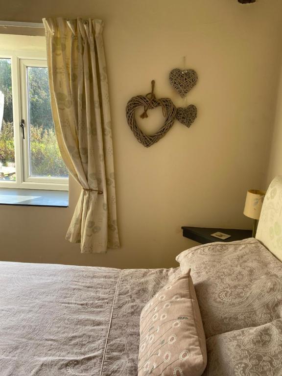a bedroom with a bed and a heart sign on the wall at Forge Cottage, Cosy Couples Retreat in the Devon Countryside, Indoor Pool, Tennis Court and Tarka Trail Access in Merton