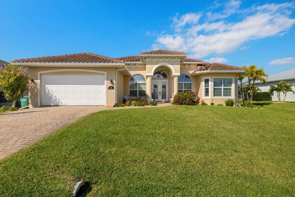 a large house with a green lawn in front of it at Villa Somada in Cape Coral