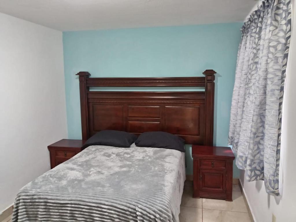 a bed with a wooden headboard in a bedroom at Mi Casa Elena in Morelia