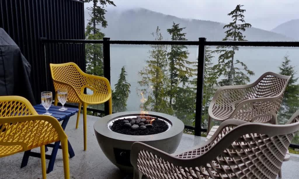 a patio with chairs and a fire pit on a balcony at Oceanfront Marina & Mountain views- pet friendly in Port Renfrew