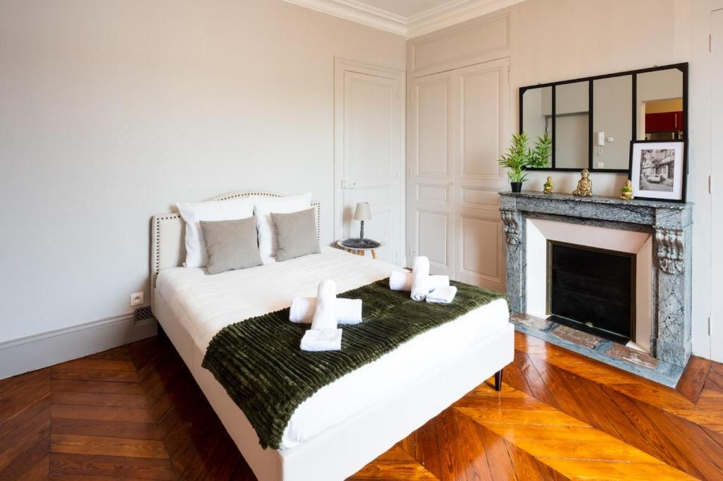 a white bedroom with a fireplace and a bed at L'Haussmannien - Hyper centre-ville Evreux in Évreux
