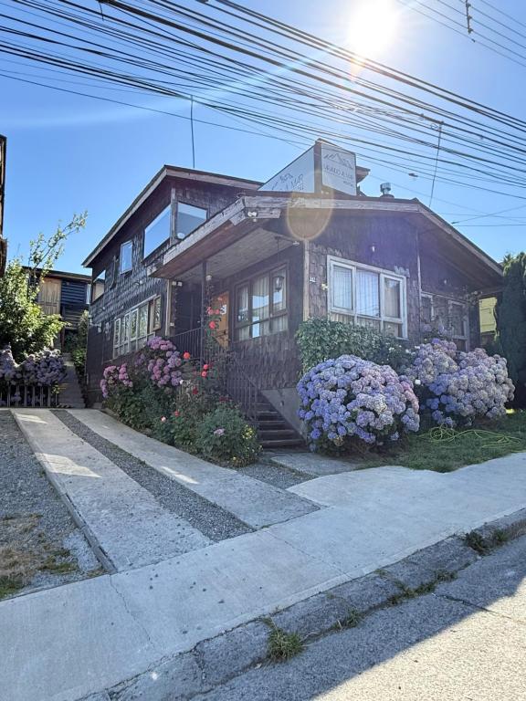 a small house with flowers in front of it at Hostal y Cabañas Mirando al Mar in Puerto Montt