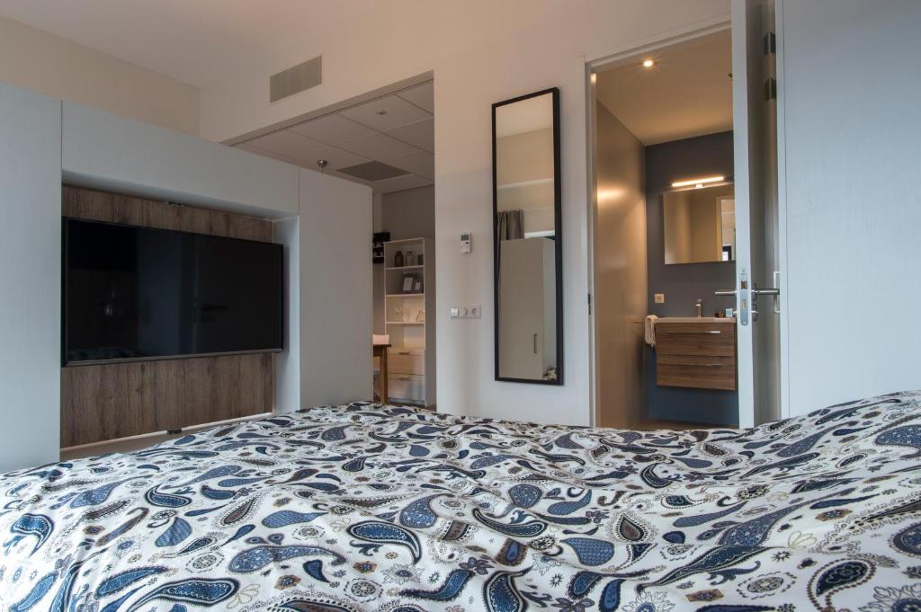 Schlafzimmer mit einem Bett mit einer blauen und weißen Bettdecke in der Unterkunft JOINN! City Lofts Houten Utrecht in Houten