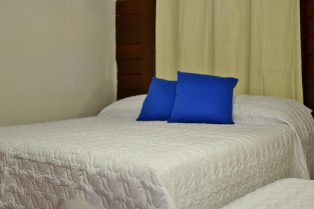 uma cama branca com uma almofada azul em Pousada Boldró Home em Fernando de Noronha