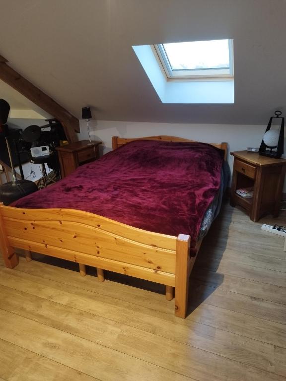 a bedroom with a wooden bed with a red bedspread at En coloc' chez Charlotte in Dunkerque