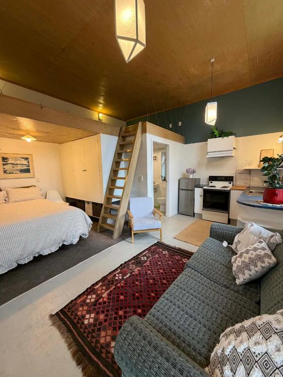 a living room with a couch and a bed and a kitchen at Self-contained studio by the beach in Paekakariki